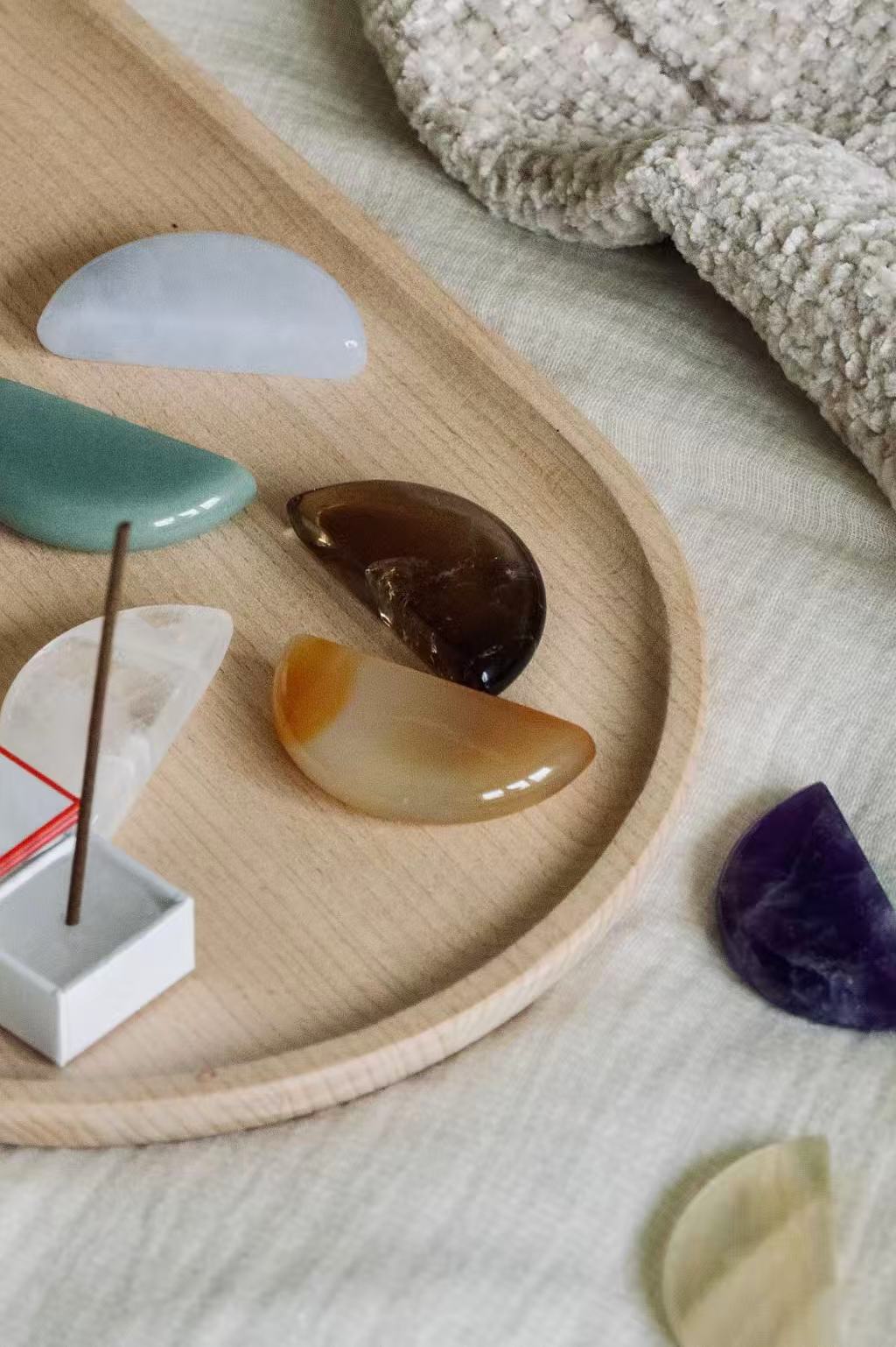 Polished chakra stones and incense arranged on a wooden tray