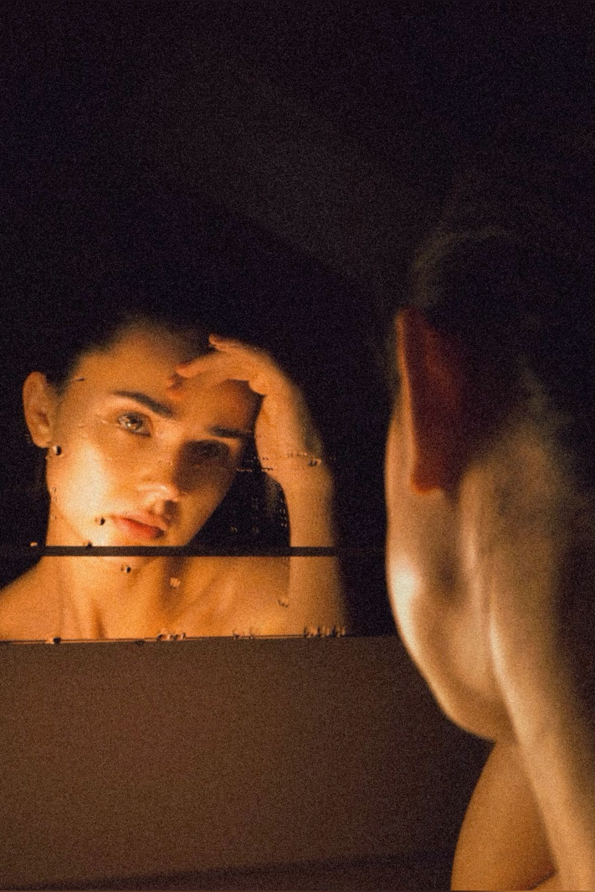 Woman looking into a mirror in warm light