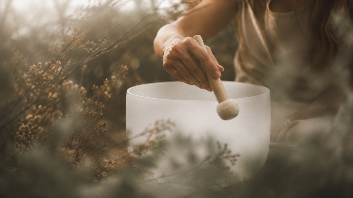 Person playing a crystal singing bowl outdoors