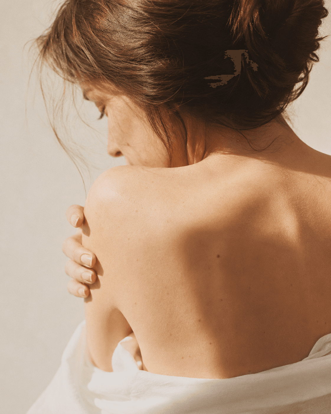 Woman gently embracing herself in warm natural light