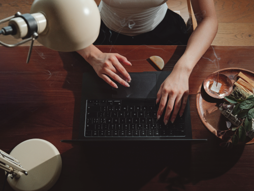 Person journaling beside a laptop during an incense ritual